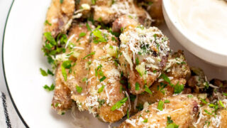 Garlic parmesan wings served on a white plate with bowl of ranch dressing.