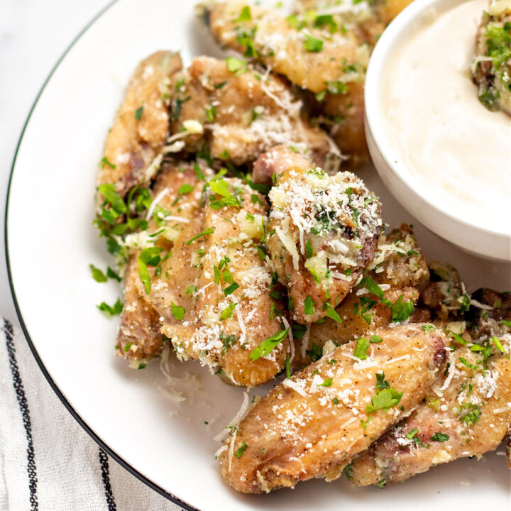 Garlic parmesan wings served on a white plate with bowl of ranch dressing.