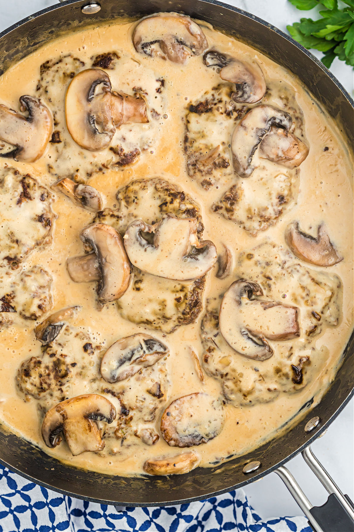 Salisbury steak with mushrooms and gravy in a skillet.