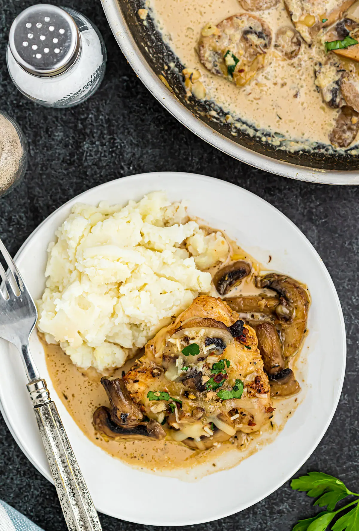 Chicken and mushrooms served on a white plate with cauliflower mash.