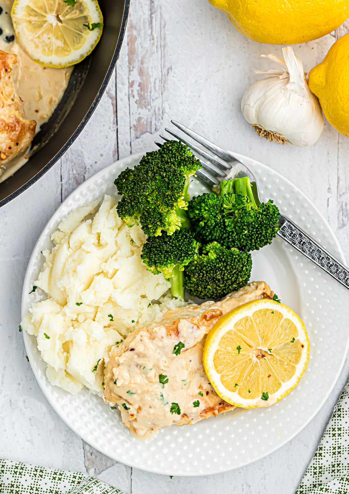 Chicken breast with lemon garlic sauce on a plate with mashed cauliflower and broccoli.