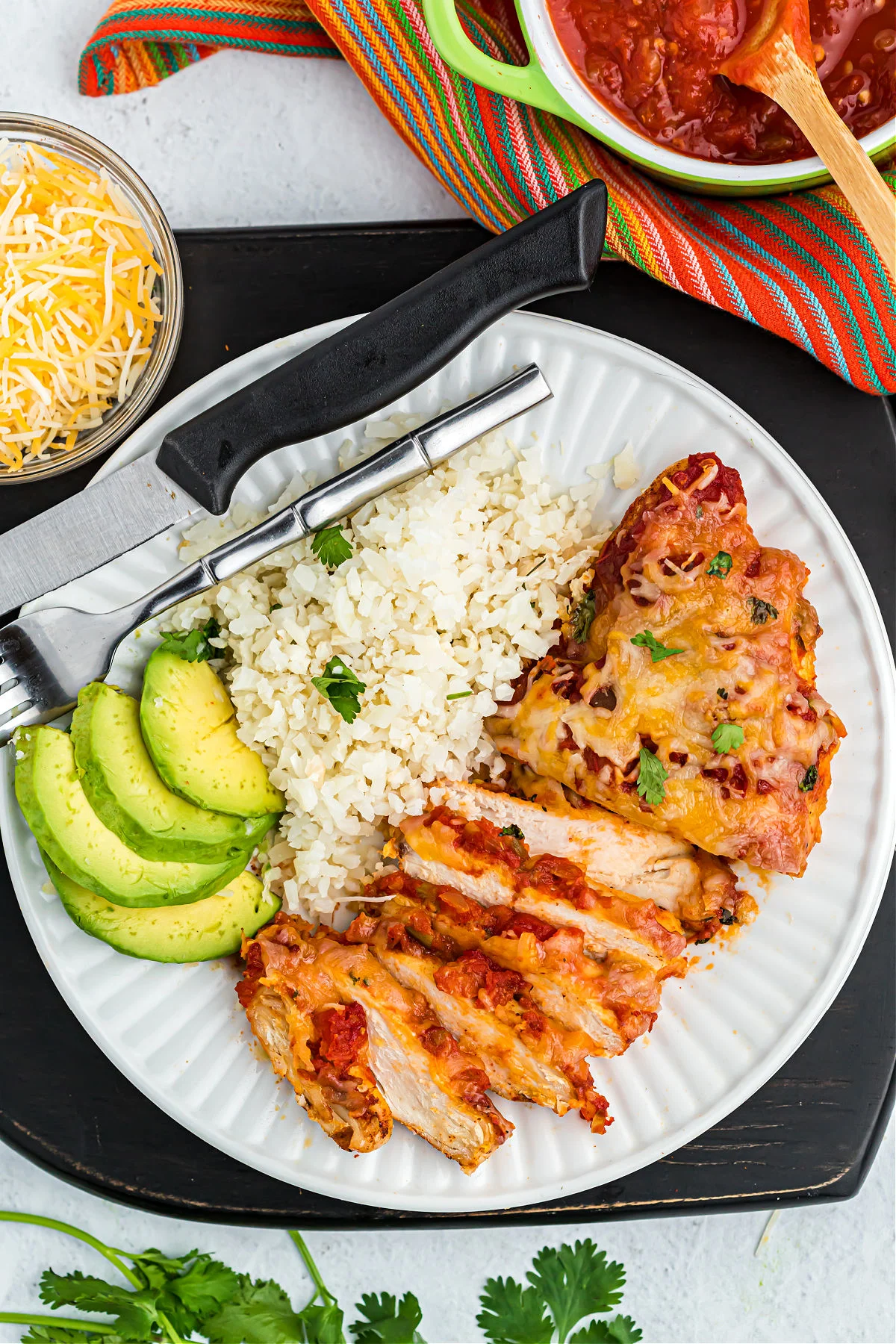Salsa chicken on dinner plate with cauliflower rice and sliced avocado.