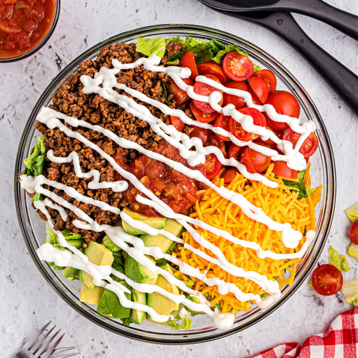Assembled taco salad drizzled with sour cream.