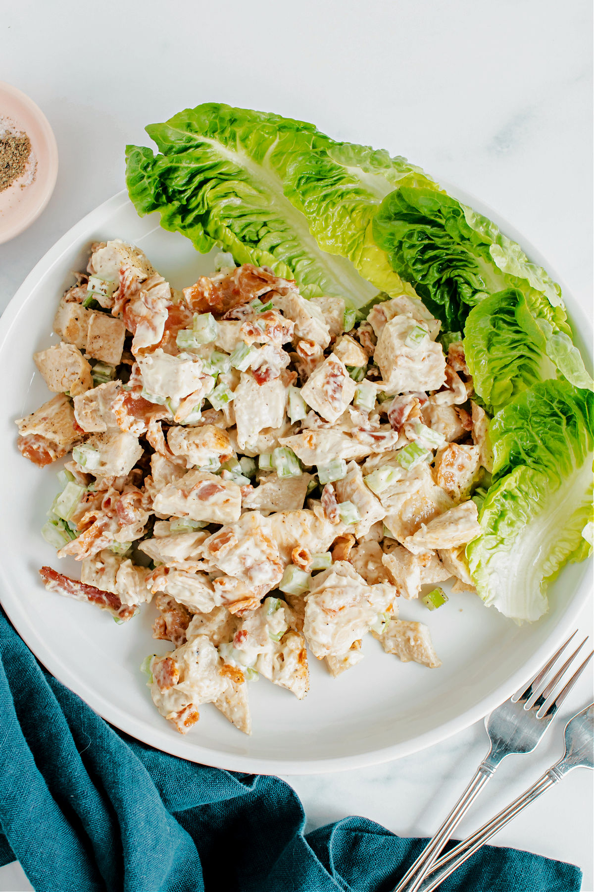 Chicken salad served on a plate with butter lettuce on the side.