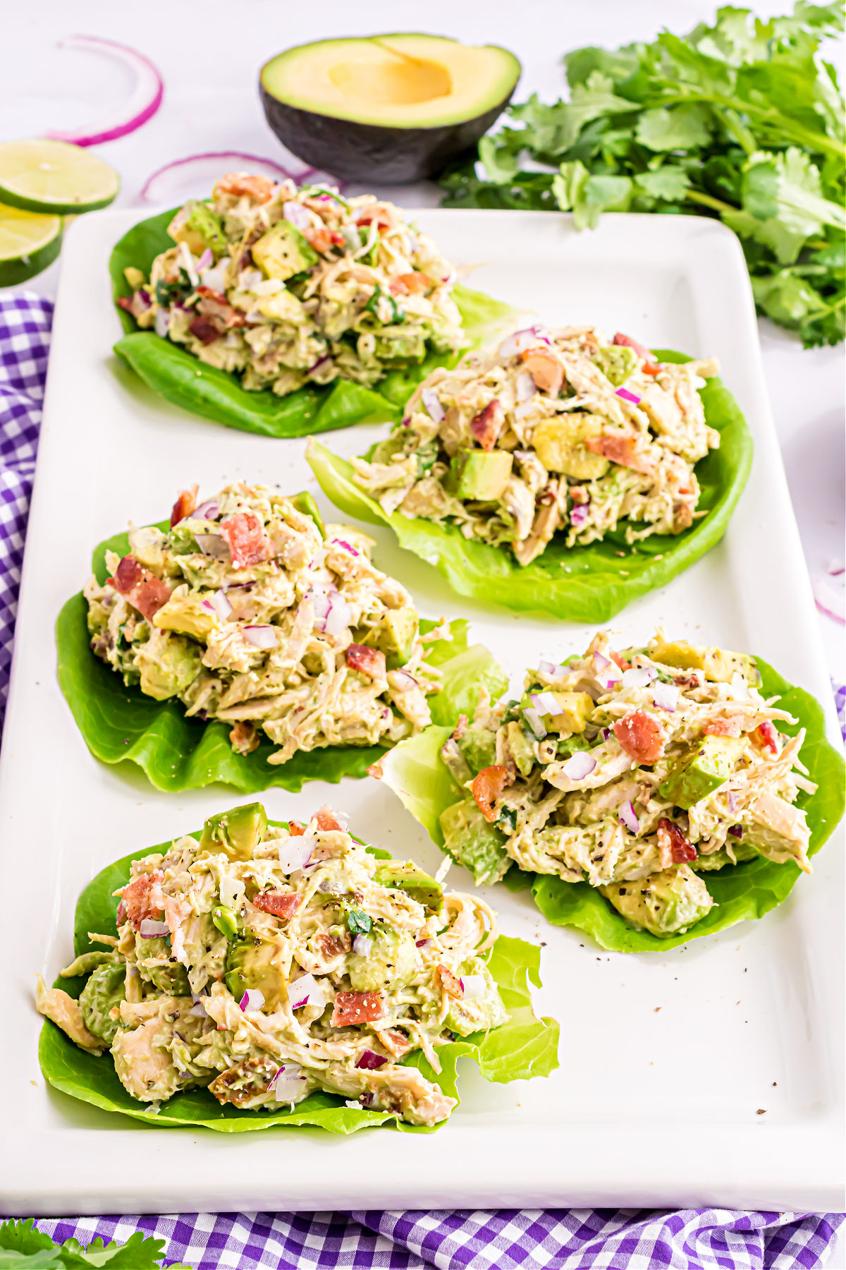 Chicken salad with avocado in a butter lettuce wrap on a white platter.