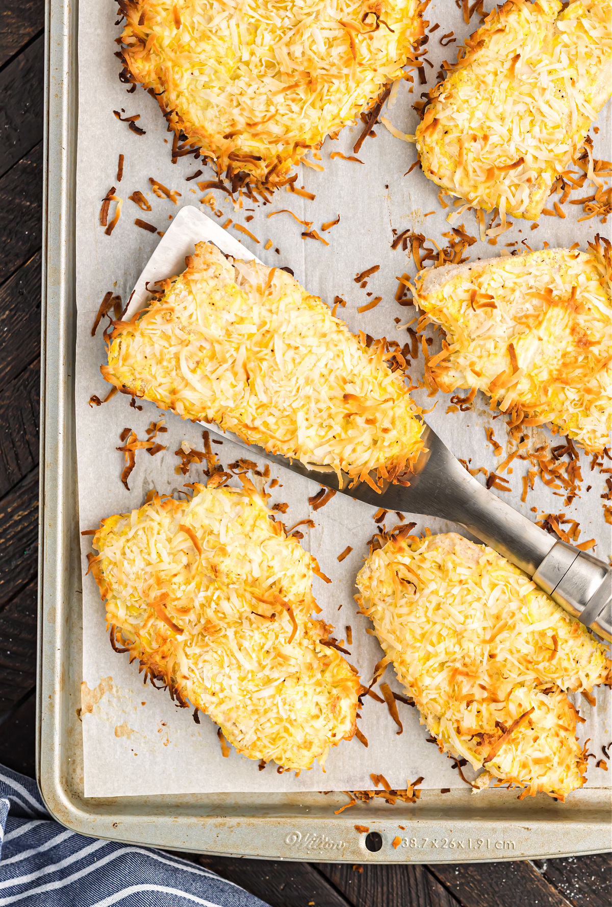 Baked coconut chicken on a parchment paper lined cookie sheet.