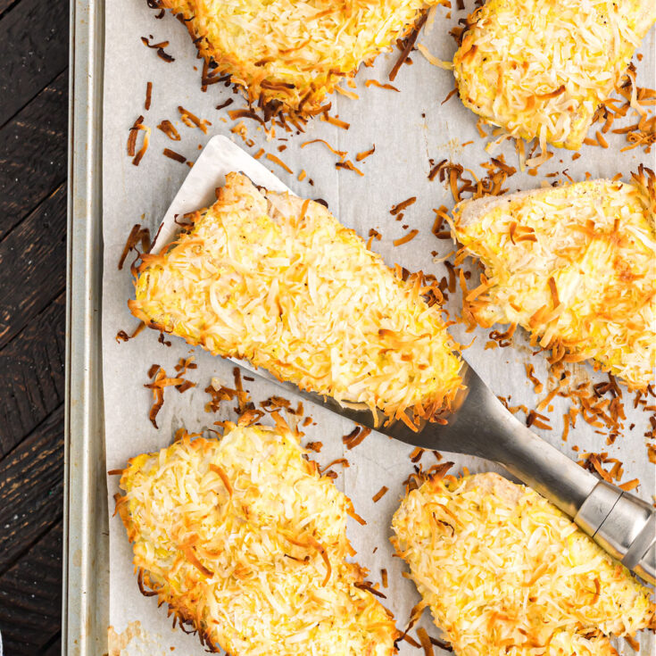 Coconut chicken baked on a parchment paper lined cookie sheet.