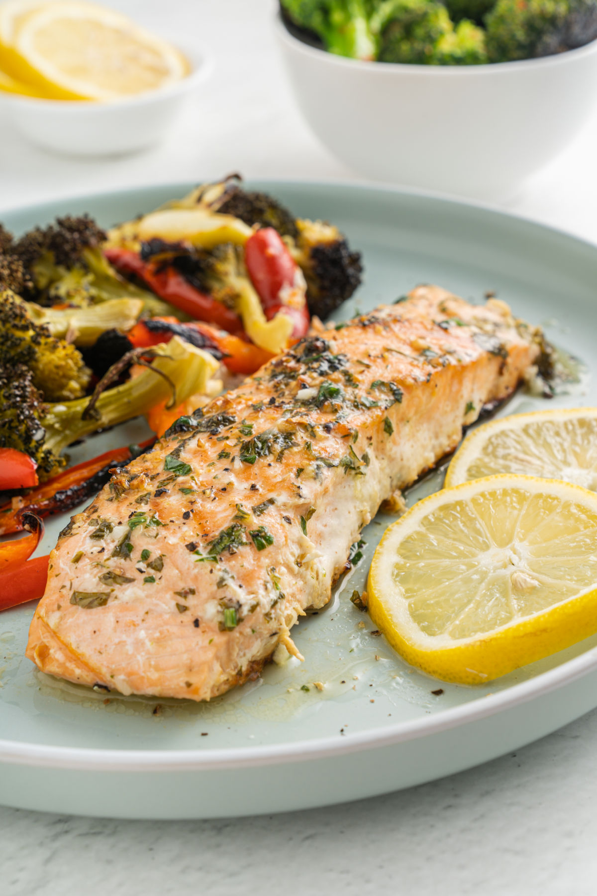 Garlic butter salmon served on a blue plate with roasted vegetables.