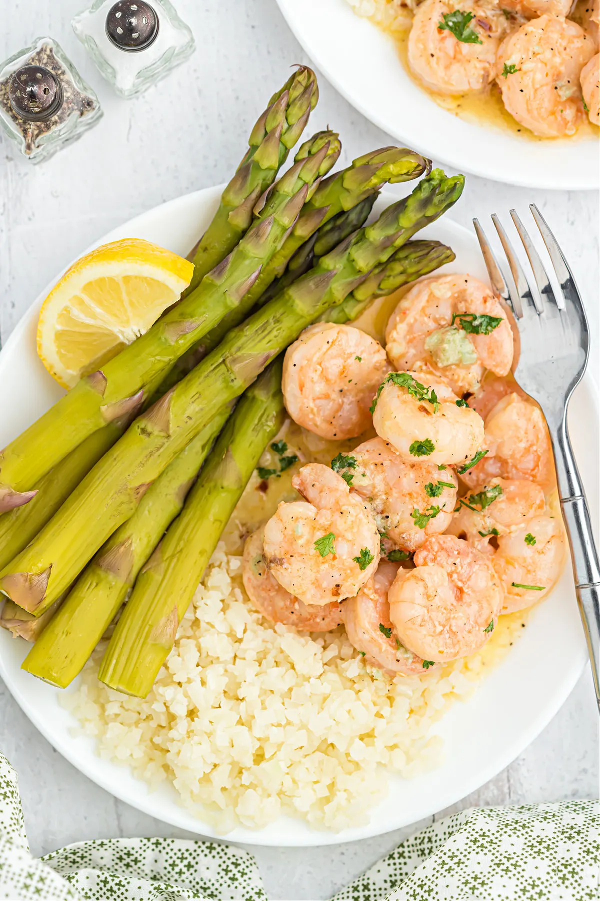 Shrimp served on a plate with asparagus and cauliflower rice.