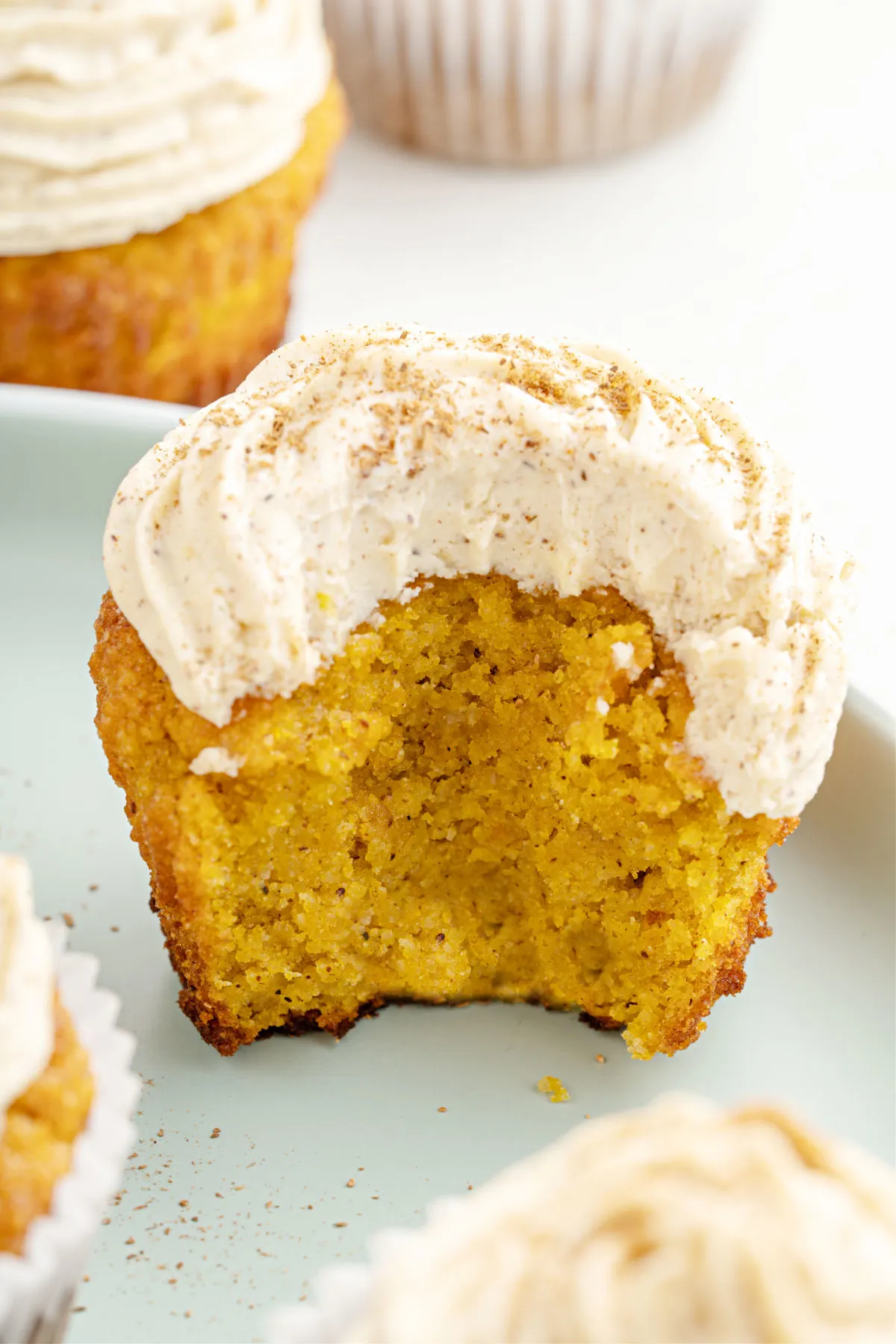 Pumpkin cupcake with cream cheese frosting and a bite taken out.