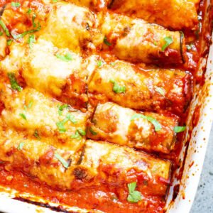 This Eggplant Rollatini is low carb take on the classic Italian meal. Strips of eggplant are rolled with a cheesy garlic filling, then baked with marinara sauce for an easy meatless keto dinner idea!